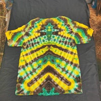 a yellow and green tie dye t - shirt on a bed